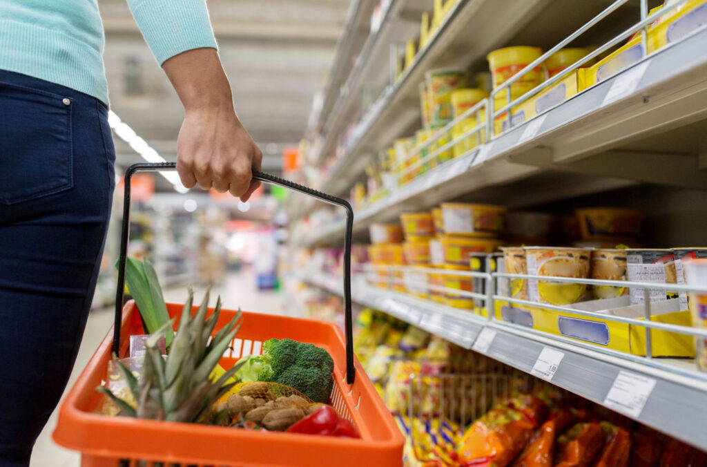 mulher com cesta de compra em supermercado. Imagem ilustrativa para texto regras do vale alimentação.