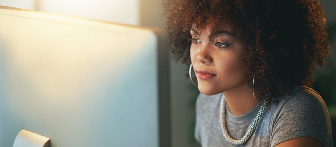 Shot of a young woman using a computer during a late shift at the office.