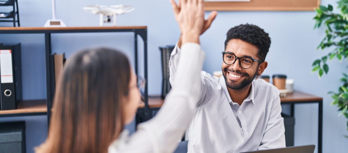 Man and woman business workers high five with hands raised up at office